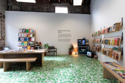room with green floor, white walls, books on walls, and a table