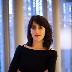 headshot photo of Daniella Rivera, standing in front of some white columns and blue lights