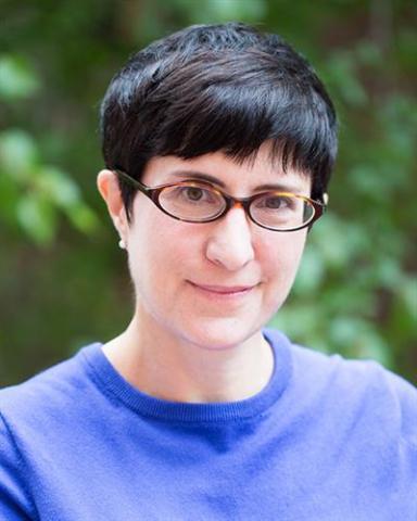 headshot photo of Heather Nathans, standing in front of green foliage