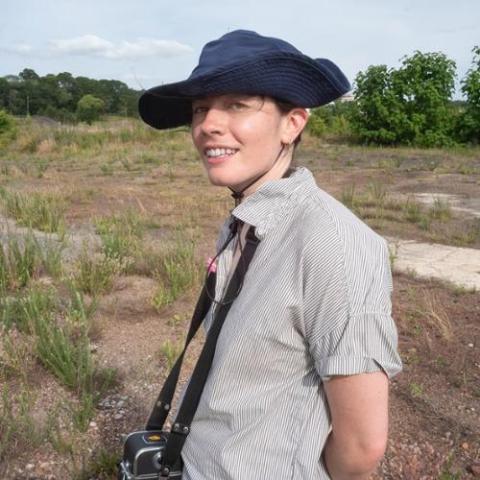 Sasha Tycko standing on a scrub plain wearing a blue hat