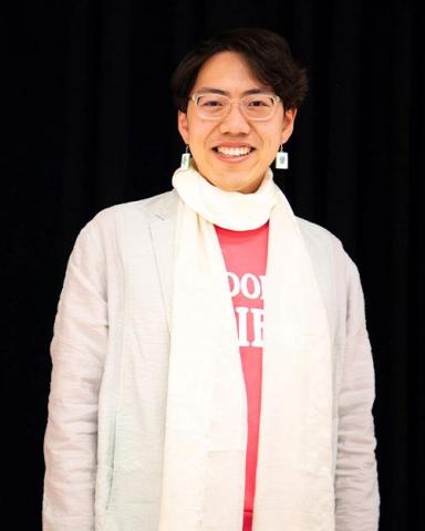 Wenxuan Xue wearing a white jacket and white scarf in front of a black background