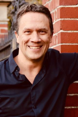 Lin Fisher standing next to a brick wall, wearing a black shirt