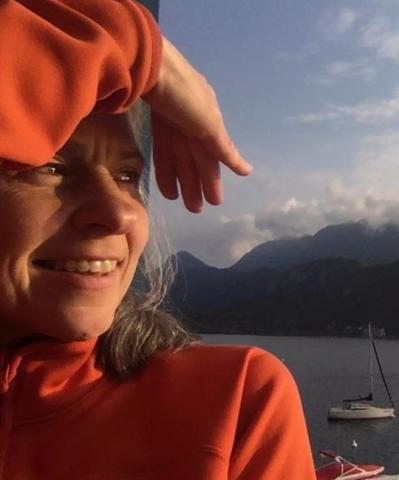 Renata Celichowska in an orange sweater, shielding her eyes from the sun