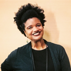 Mary smiling in a black jacket with a beige background