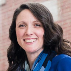 Melinda Latour in a blue jacket with buildings behind her