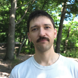 Omid in a white shirt with trees behind him