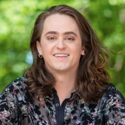 Jo Michael Rezes in a black flowery shirt with trees in the background