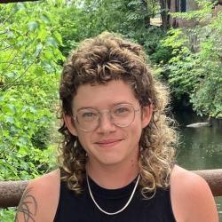 Arlo Fosburg smiling at the camera with trees and water behind