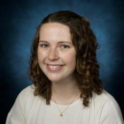 Haley Mullen in front of a blue background, smiling