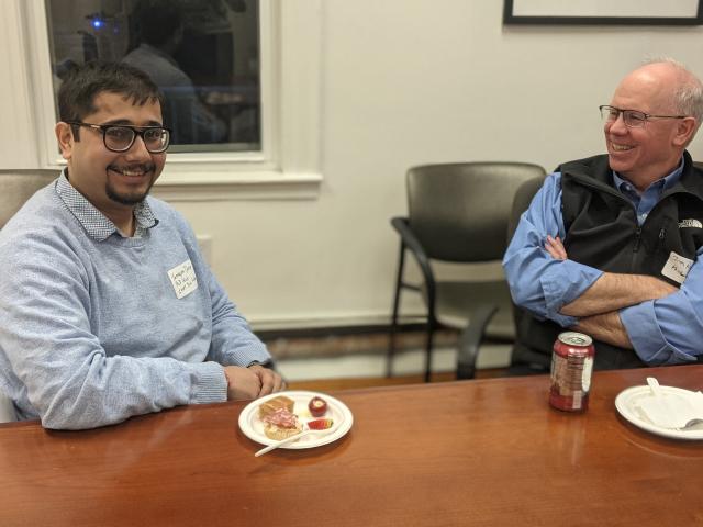 two men smiling at a table with plates in front of them