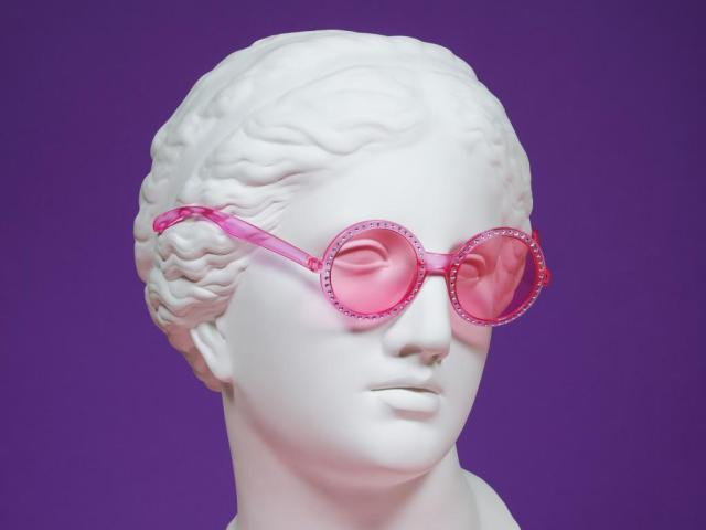 stone female statue head wearing pink plastic glasses