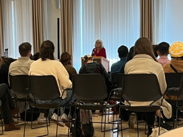 Louise Halfe at a podium, and students in chairs listening