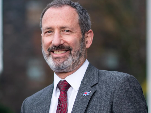 headshot of dean Jim Glaser, in red tie and grey jacket