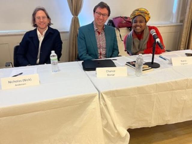 Three people smiling, sitting at a table