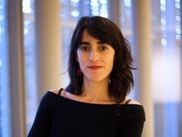 headshot photo of Daniella Rivera, standing in front of some white columns and blue lights