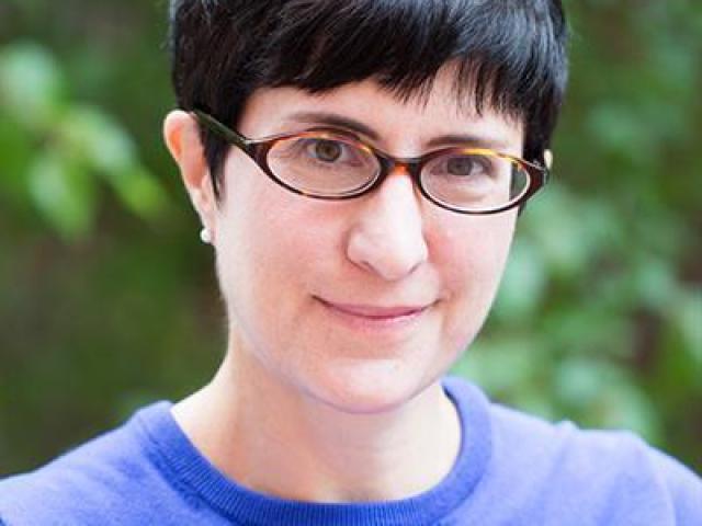 headshot photo of Heather Nathans, standing in front of green foliage