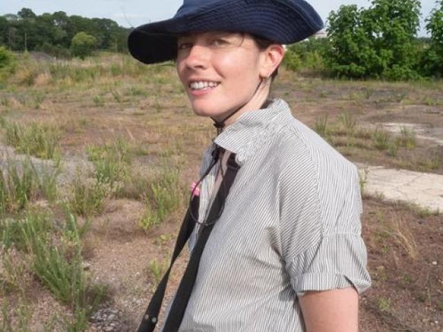 Sasha Tycko standing on a scrub plain wearing a blue hat