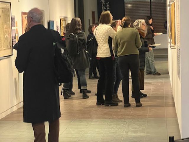 a crowd of people looking at a photo exhibit in a hallway