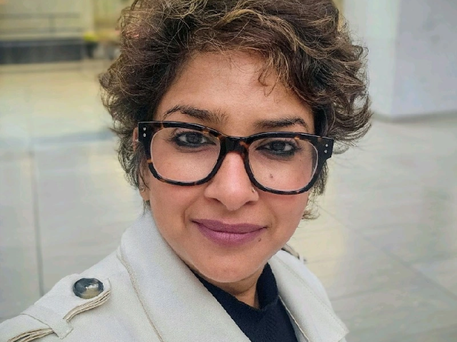 Namrata jain sitting in a room with glass cases and a white pillar