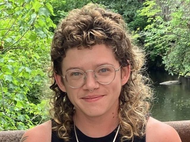 Arlo Fosburg smiling at the camera with trees and water behind