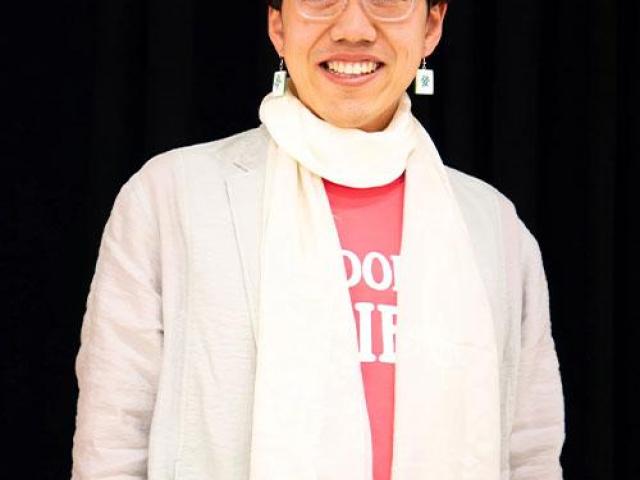 Wenxuan Xue wearing a white jacket and white scarf in front of a black background