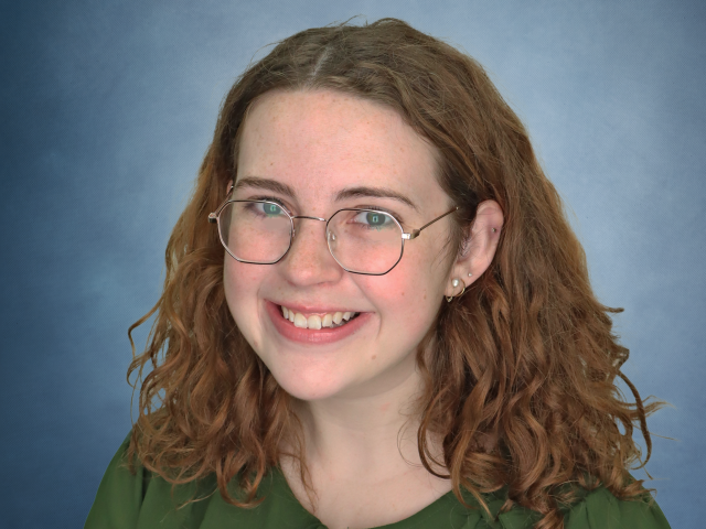 Haley Mullen in front of a blue background, smiling