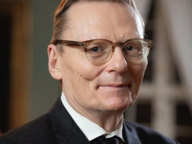 James Robinson in a suit with a window and door in the background