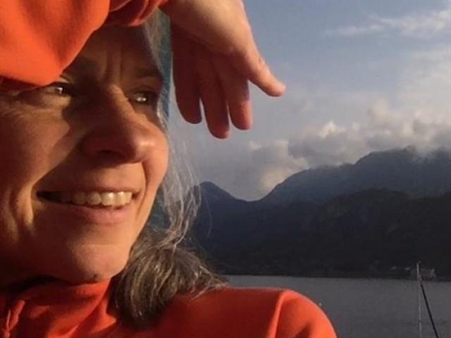 Renata Celichowska in an orange sweater, shielding her eyes from the sun