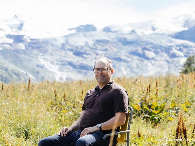 Rob Wallace sitting in a field with mountains in the distance